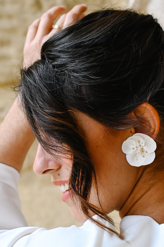 Boucles d'oreilles Abélia Boucles d’oreilles composées d’une fleur en crêpe de soie entièrement brodée à la main de véritables perles d’eau douce. La monture est en plaqué or trois microns. Ces boucles d’oreilles sont disponibles en clip pour les oreilles non-percées.